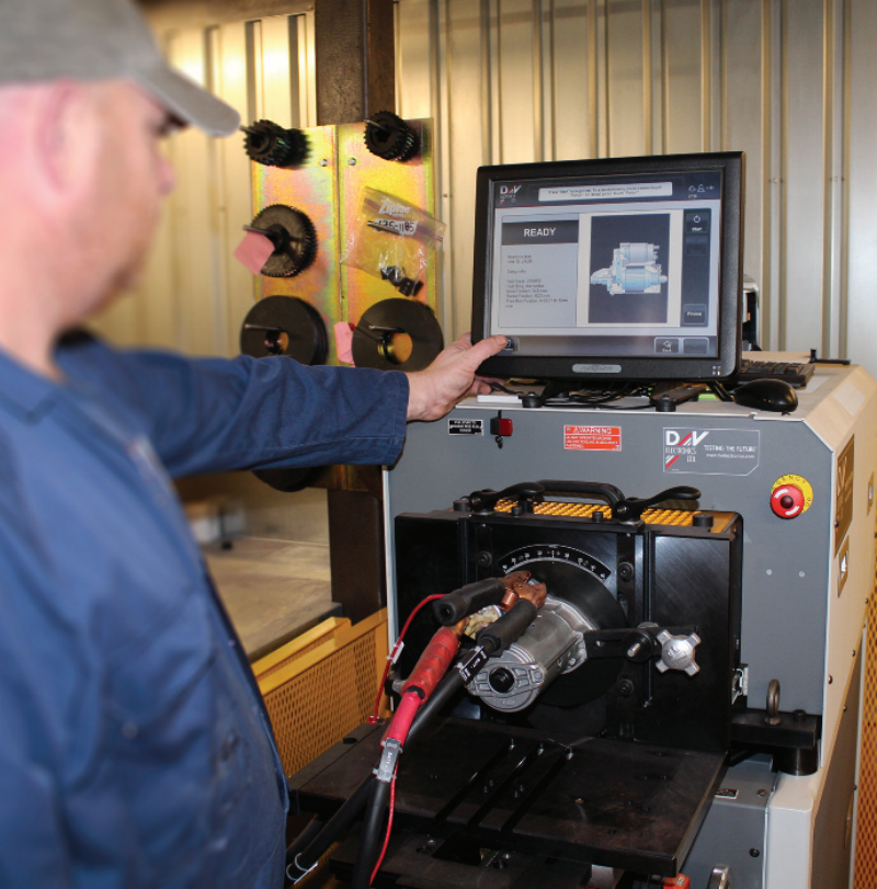 Technician operating a DV Electronics automated testing rig for evaluating remanufactured starter motors and alternators.