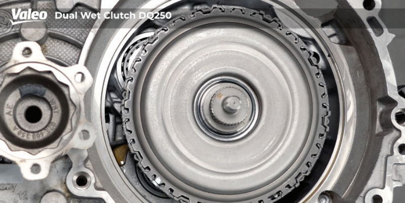 Close-up, top-down studio view of the Valeo Dual Wet Clutch DQ250 assembly mounted in the transmission housing, showing the successfully repositioned dual clutch pack with its outer notched locking ring fully engaged.